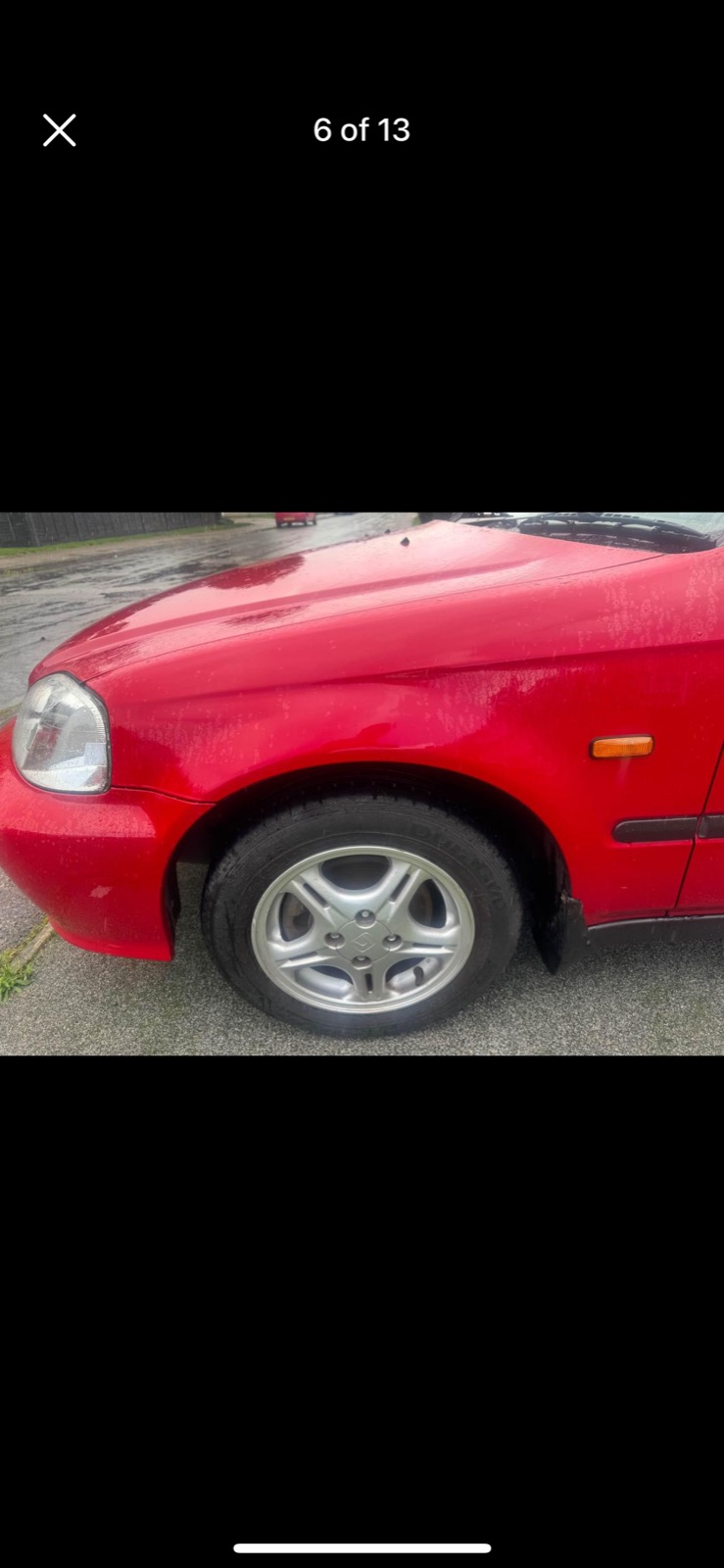 Close-up of the front fender and stock alloy wheel on the red Civic EK, from the original listing photos