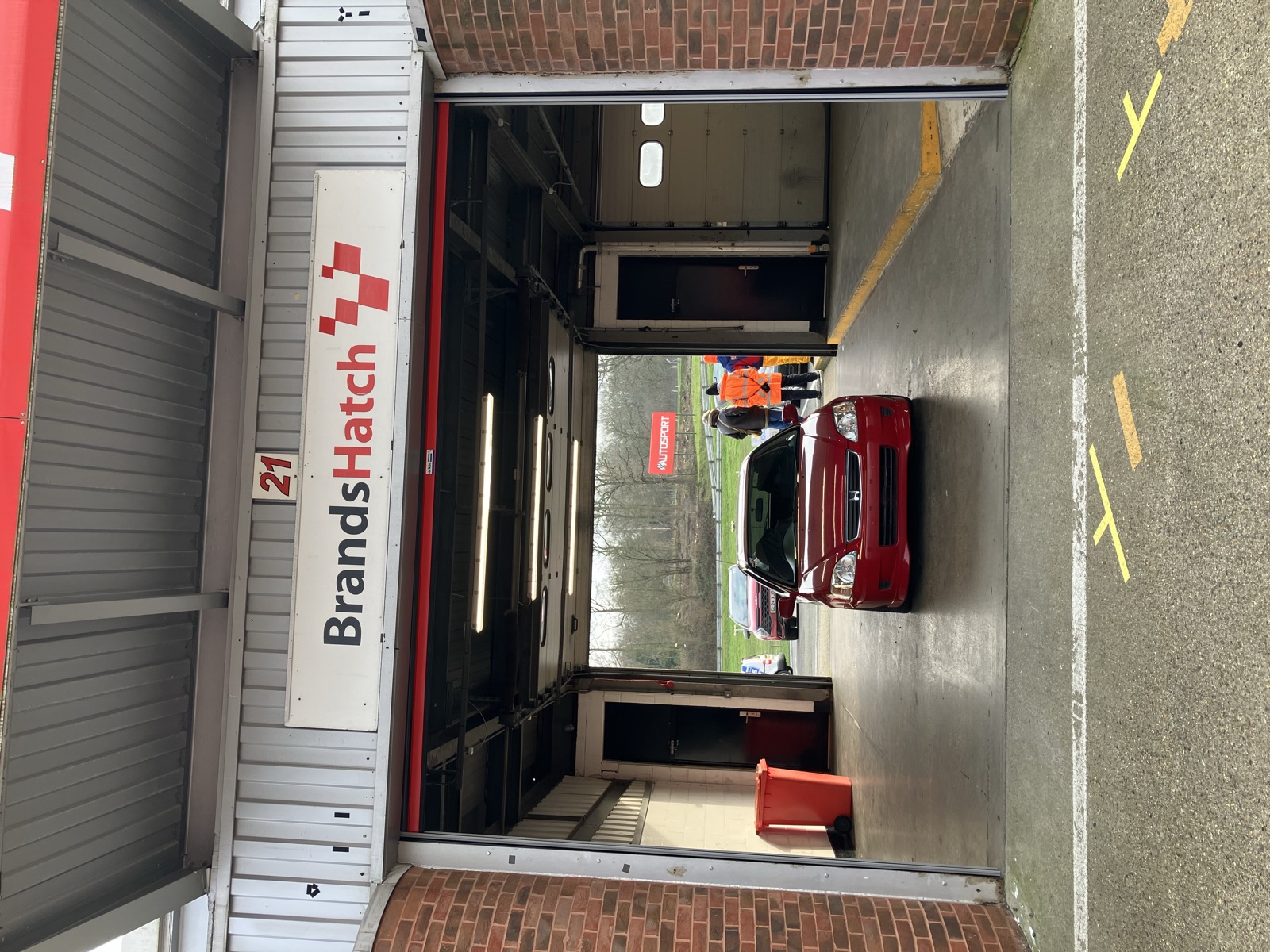 The red Civic EK driving into a garage at Brands Hatch circuit, marshal visible