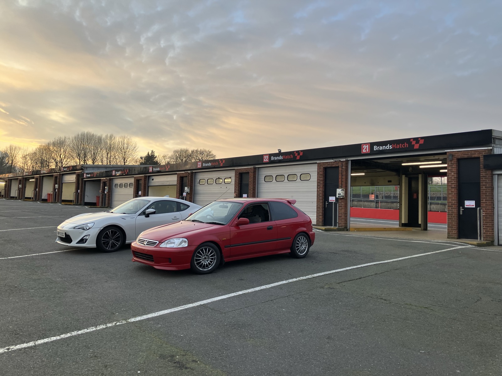 The red Civic EK parked in the paddock at Brands Hatch next to a white Toyota GR86