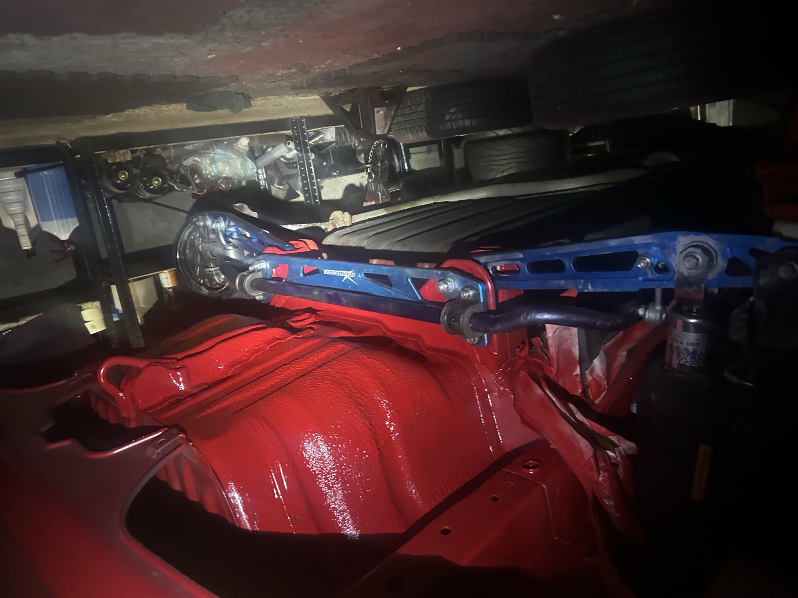 A blue front strut bar installed across the engine bay, underside view