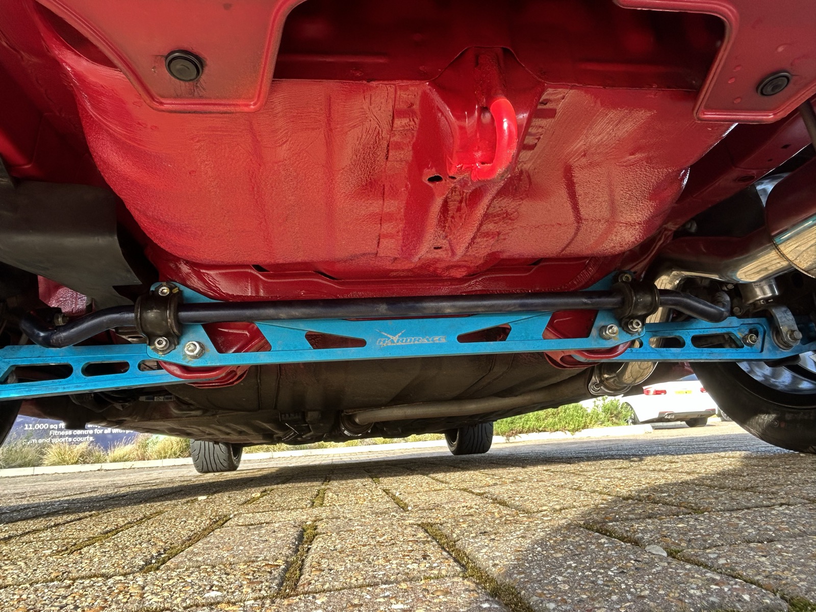 A blue rear strut bar installed underneath the back of the car
