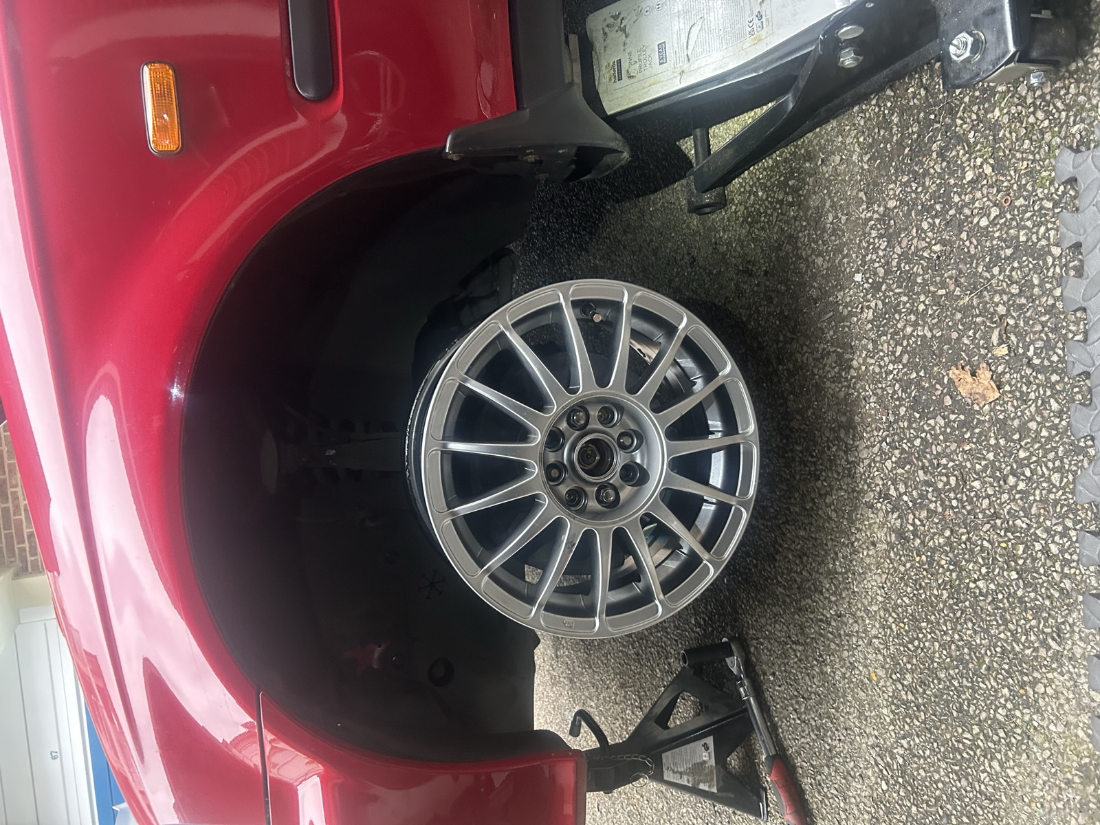 A Team Dynamics lightweight alloy wheel fitted to the red Civic, car raised on jack stands